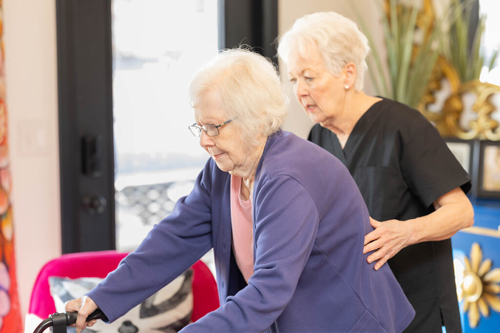 How to talk to seniors about caregiving, caregiver gently assisting elderly woman with mobility at home, illustrating how to talk to your parents about senior living and offering supportive resources for caregivers