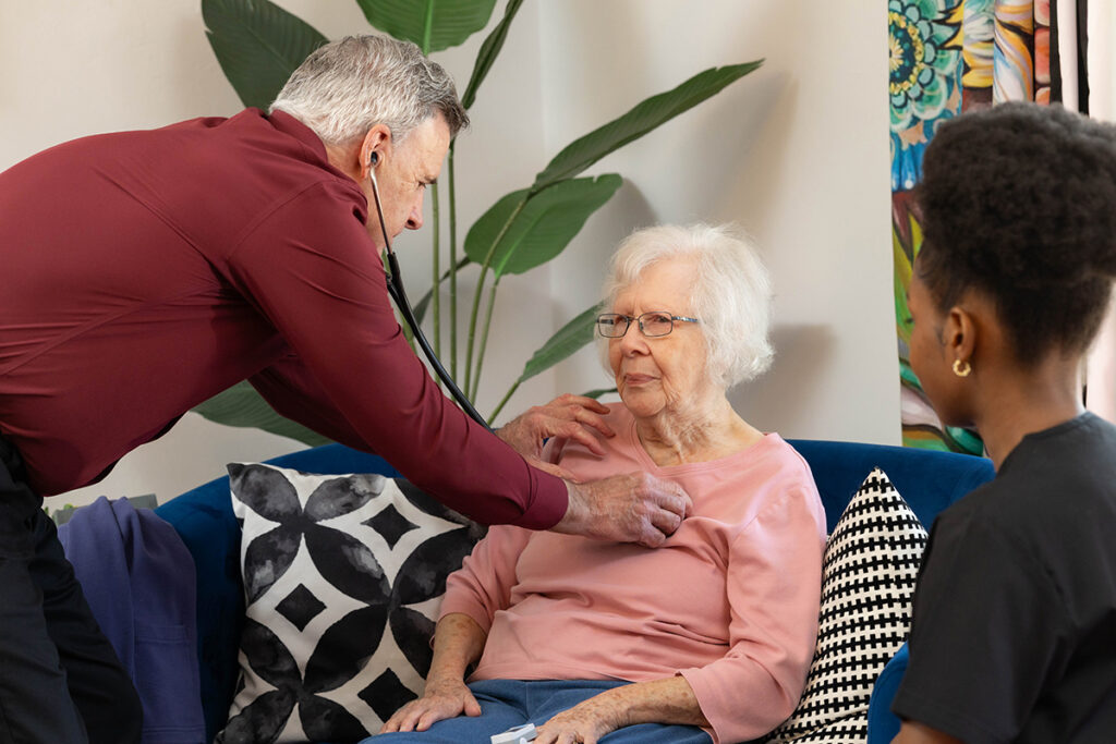 Senior care professional checking an elderly woman during an in-home care and wellness visit