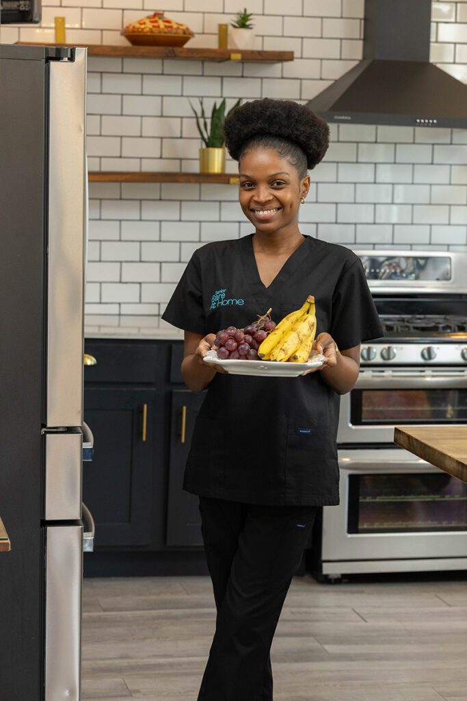 Caregiver carrying fresh fruit plate during in-home senior care visit