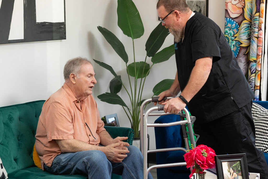 Caregiver assisting a senior man with mobility support during an in-home care visit