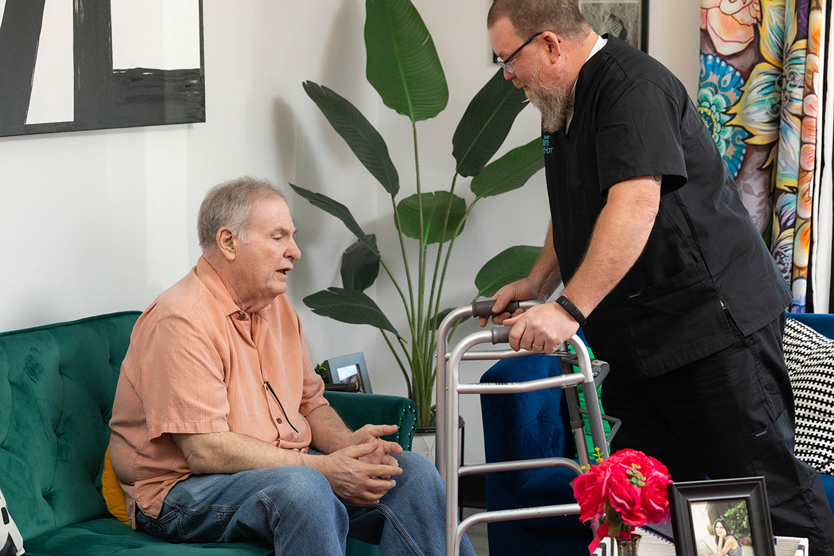 Caregiver assisting a senior man with mobility support during an in-home care visit