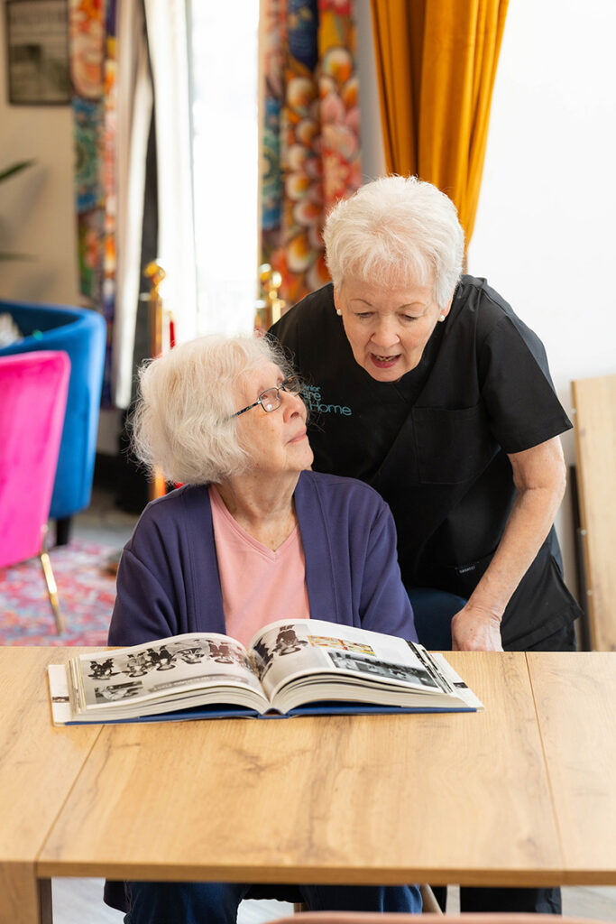 Caregiver reviewing photo album with senior woman during in-home care visit